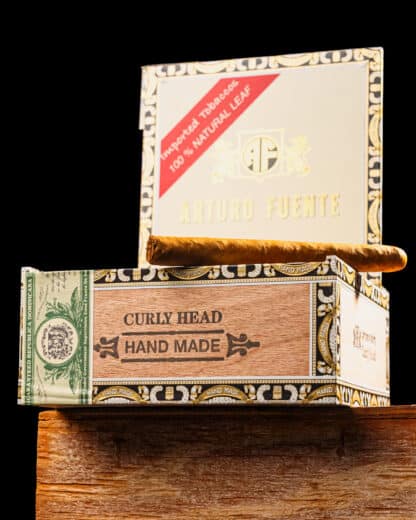 Open box of Arturo Fuente Curly Head Cigars with one cigar visible