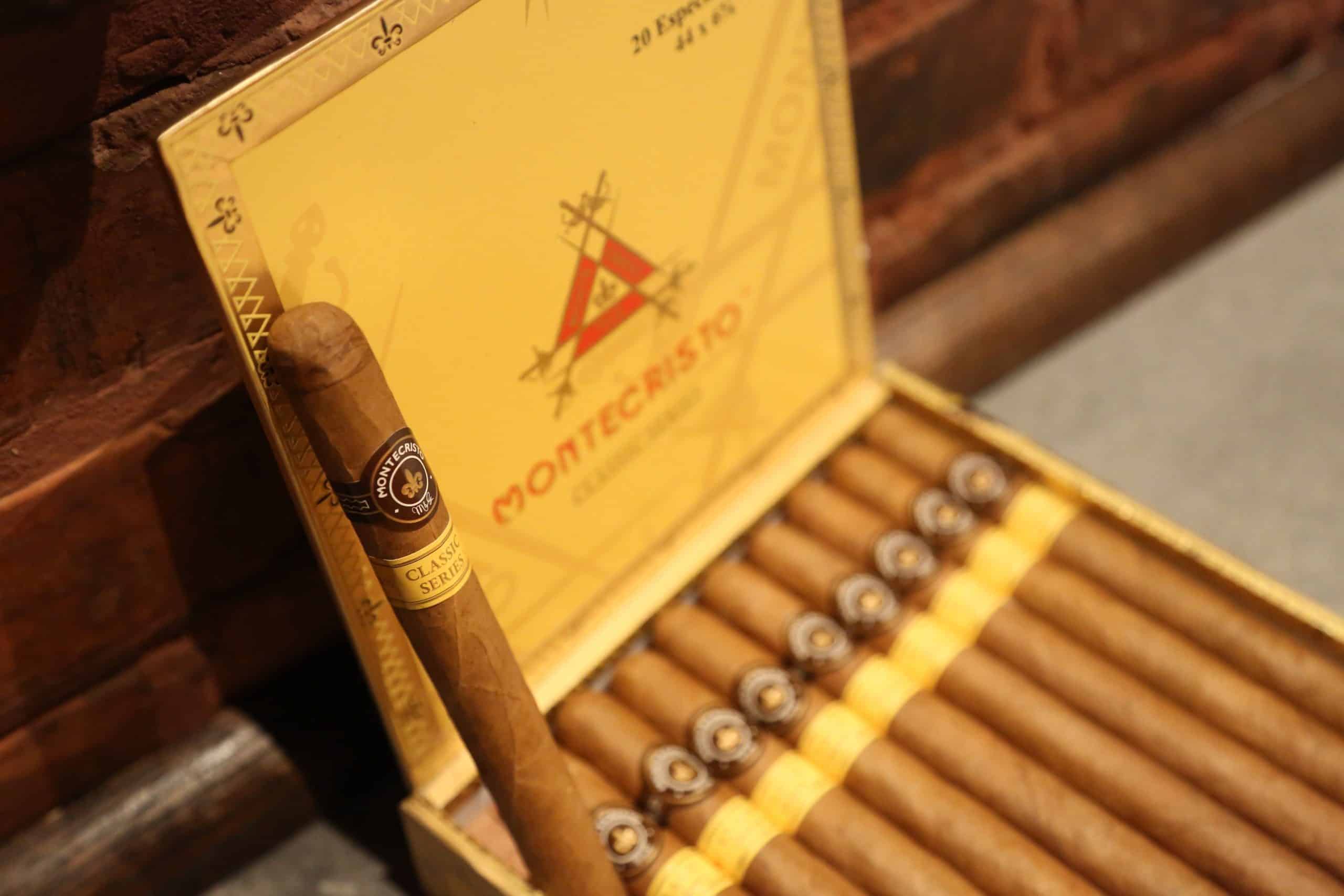 Single cigar leaning on an open box of Montecristo Classic Series cigars