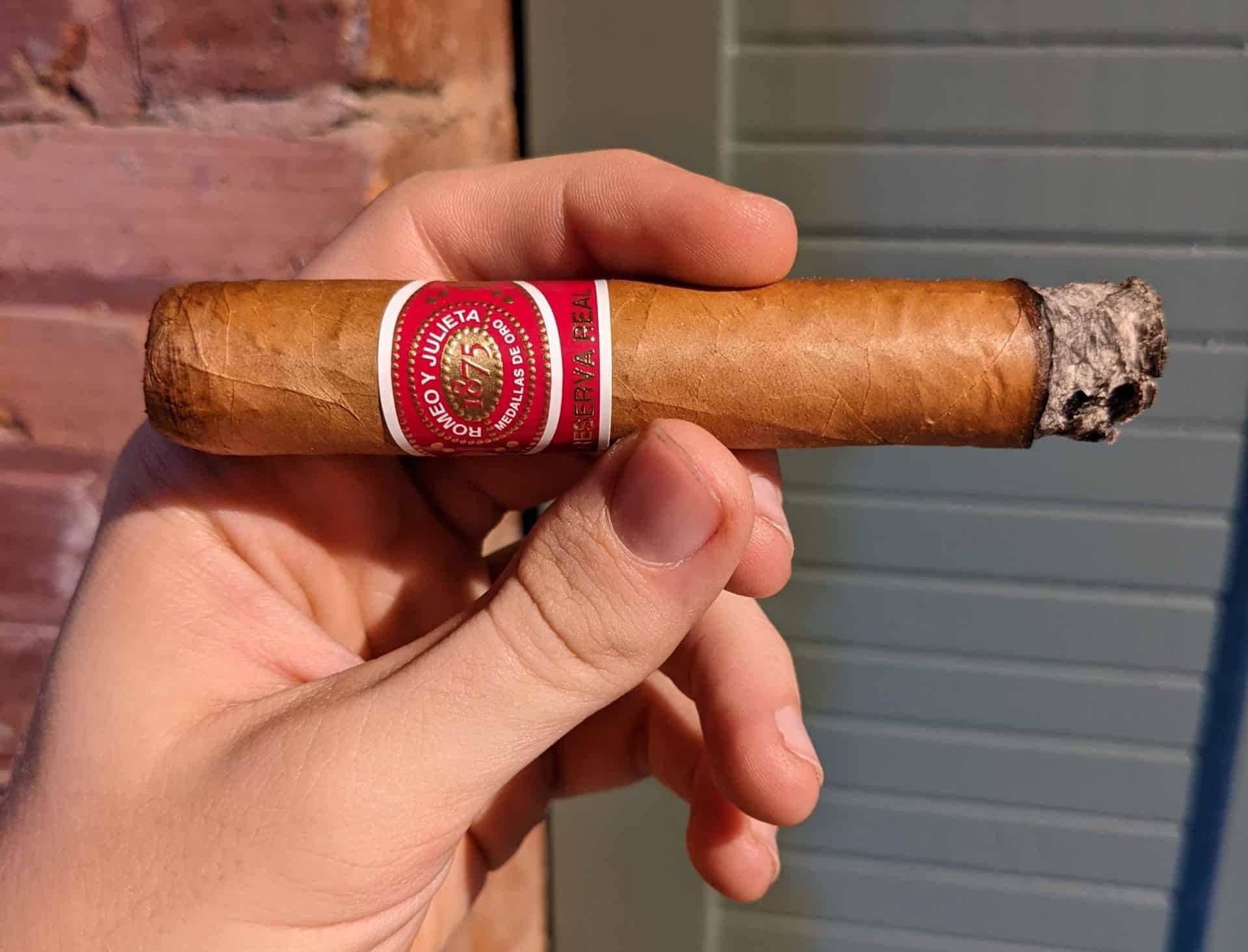 Hand holding a Romeo Y Julieta Reserva Real cigar lightly-ashed