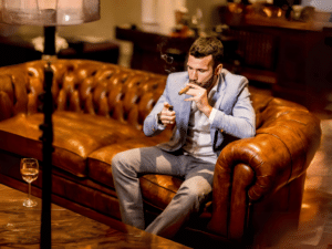 Man lighting a cigar, sitting in a cigar lounge